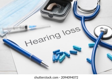 Text HEARING LOSS With Stethoscope And Pills On White Wooden Background, Closeup