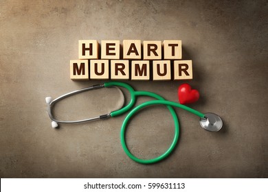 Text HEART MURMUR Made Of Wooden Cubes And Stethoscope On Color Background