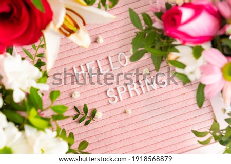 Text Hello Spring on pink letter board and frame of blooming flowers. Concept Springtime mood and happiness