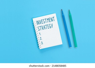 The text Investment strategy is written on a notebook page. An investment strategy is what guides the investor when making decisions based on goals, risk tolerance and future capital requirements.