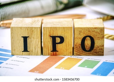 Text "IPO" on wood cube lay on chart candle document paper , stock investment concept.   