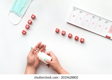 Text Long Covid On Red Cubes. Hand With Pills. Text Long Covid, Patient Hands With Pills. German Text On Weekly Planner Means Days Of The Week. Cancellation, Change Of Plans. Chronic Covid Illness