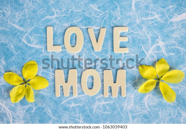 Text \'love mom\' with spring\
flower on blue background. greeting card concept,mother\'day\
concept.