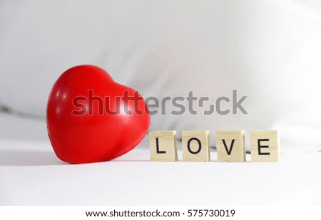 Text LOVE and Red heart on the bed.