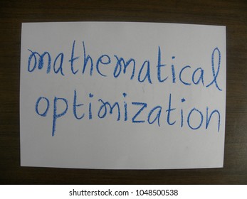 Text Mathematical Optimization Hand Written By Blue Oil Pastel On White Color Paper