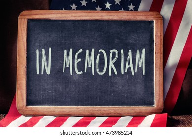 The Text In Memoriam, A Latin Phrase For In Memory, Written In A Chalkboard And A Flag Of The United States, On A Rustic Wooden Surface