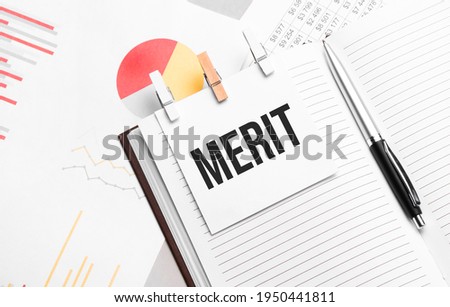 text MERIT on stickers on the diary with office tools