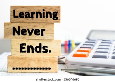 Text message Learning never ends on wooden with office table. Business concept