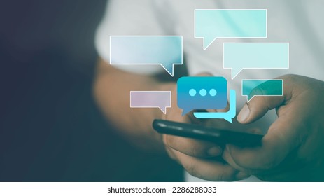 Text messages in cellphone screen with abstract hologram speech bubbles. Instant messaging app. Texting, group chat, sexting or sms concept. Customer service help desk with live support chatbot. - Shutterstock ID 2286288033