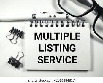 Text MULTIPLE LISTING SERVICE Writing On Notebook With Pen,paper Clips And Glasses On White Background.