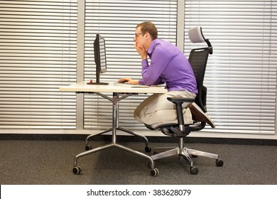 text neck - man in slouching position kneeling on ergonomic chair working with computer at desk