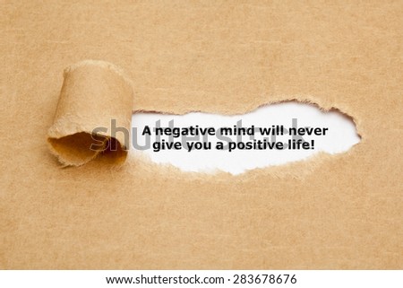 The text A negative mind will never give you a positive life, appearing behind torn brown paper. Motivational quote.