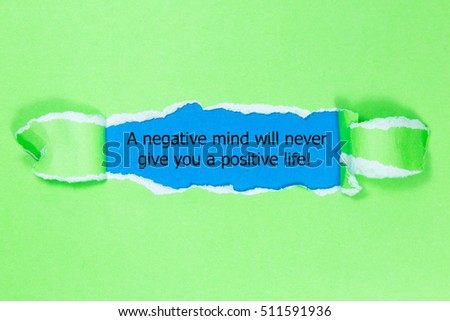 The text A negative mind will never give you a positive life, appearing behind torn paper. Motivational quote.