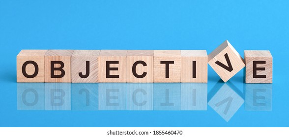 Text objective on wood cube block, stock investment concept. The text objective is written on the cubes in black letters, the cubes are located on a blue glass surface