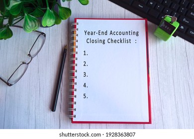 Text On Notebook With Tally Counter Clicker, Glasses, Pen, Keyboard And Green Plant On The Table - Year End Accounting Closing Checklist