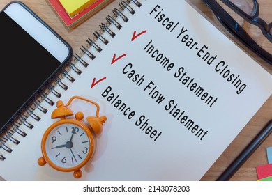 Text On Notepad With Alarm Clock On Wooden Desk - Fiscal Year End Closing Checklist. Business And Accounting Concept