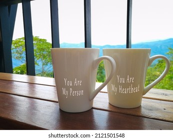 Text on two porcelain cups facing the mountain view - You are my person, you are my heartbeat