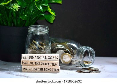 Text On Wood Block With Australian And European Coins On Table Surface With Dark Background - Set Financial Goals, Save For The Short Term And Invest For The Long Term. Financial Plan Concept