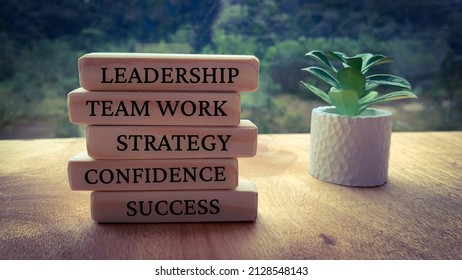 Text On Wooden Blocks - Leadership, Team Work, Strategy, Confidence And Success. With Plants And Blurred Nature Background.