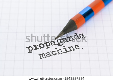 Text Propaganda Machine written on bright background and a pencil
