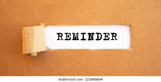 Text REMINDER Appearing Behind Torn Brown Paper.