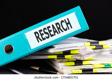 Text RESEARCH Is Written On A Folder Lying On A Stack Of Papers With A Pen On The Table. Business Concept