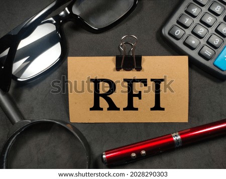 Text RFI (Request For Information) writing on brown card with magnifying glass, pen,calculator and glasses on black background.