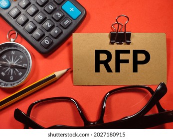 Text RFP (Request For Proposal) Writing On Brown Card With Compass, Pencil,calculator And Glasses On Red Background.