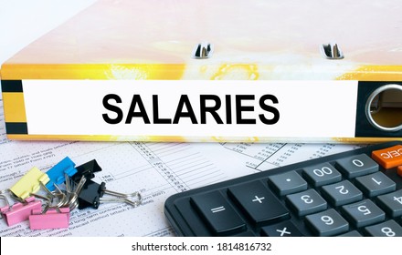 Text Salaries on the folder that is located on the financial reports with calculator and stationery clips. Business and financial concept