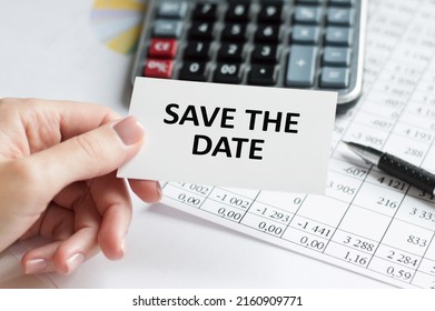 Text Save The Date Inscription On A Business Card In The Hands Of A Man On The Background Of An Office Desk, A Business Concept