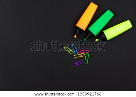 text separators in different colors and paper clips on a black background