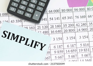 Text SIMPLIFY Inscription On A Blue Card On The Office Desk Among The Reports