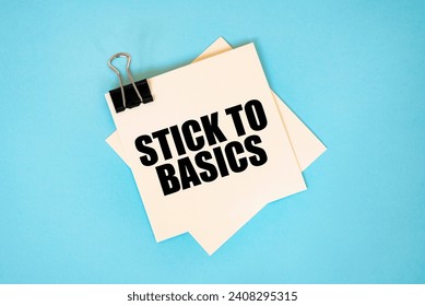Text STICK TO BASICS on sticky notes with copy space and paper clip isolated on red background. Finance and economics concept.