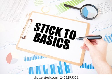 Text STICK TO BASICS on white paper sheet and marker on businessman hand on the diagram. Business concept