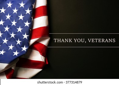 Text Thank A You, Veterans on black background near American flag