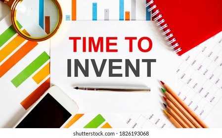 Text TIME TO INVENT on notepad with office tools, pen on financial report