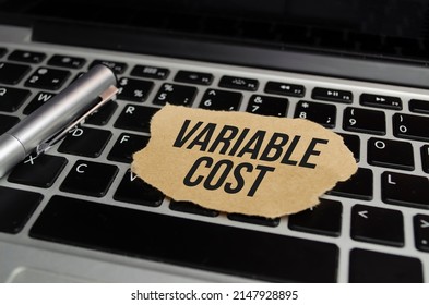 Text VARIABLE COST on white paper on clipboard with chart and calculator