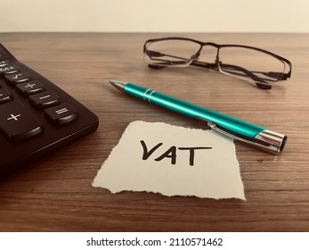 Text vat with pen, calculator and glasses on office desk, financial concept - Shutterstock ID 2110571462