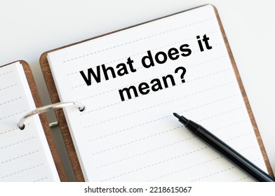 text what does it mean written on notepad with pencil and white background. High quality photo