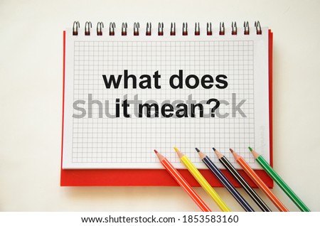 text what does it mean written on notepad with pencils and white background. High quality photo