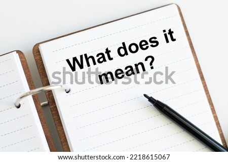 text what does it mean written on notepad with pencil and white background. High quality photo