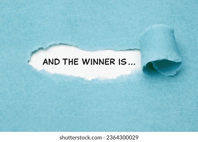 Text And the Winner is ... appearing behind torn blue paper. Winner announcement concept.