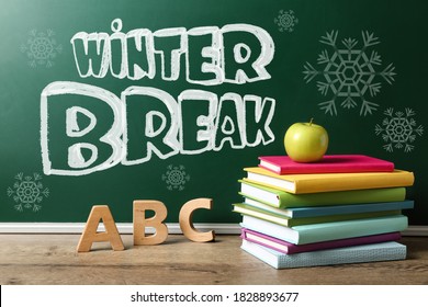 Text Winter Break On School Chalkboard Near Table With Books, Letters And Apple