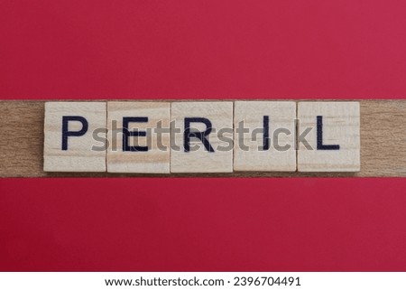 text the word peril from gray wooden small letters with black font on an red table