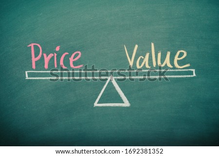 Text word price and value balance on seesaw drawing writing on chalkboard or blackboard background. Concept of price, value analysis in product, business and investment. Real photo, not illustration.