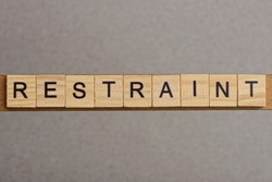 Text The Word Restraint From Brown Wooden Small Letters With Black Font On An Gray Table