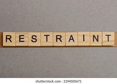 text the word restraint from brown wooden small letters with black font on an gray table - Shutterstock ID 2194505671