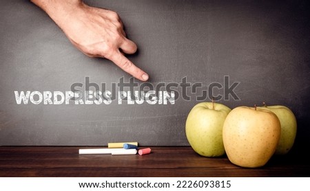 Text WORDPRESS PLUGIN on a dark blackboard. Apples on a wooden table.