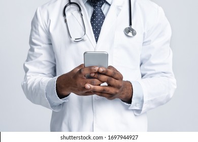 Text your doctor during isolation. Cropped of african doctor holding mobile phone over white studio background