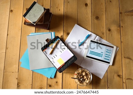 Textbook, notes, tablet and cereals on floor. Studying for final exam concept.